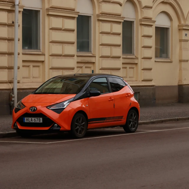 a small orange car driving down the road
