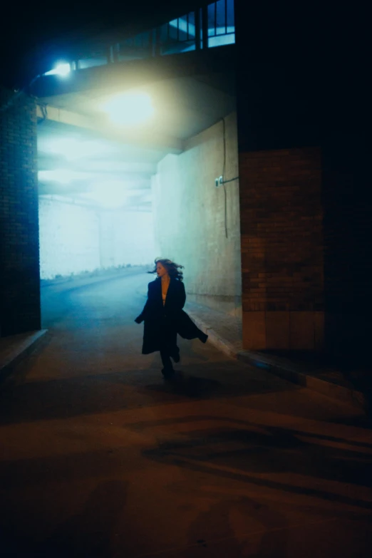 the person is walking under an overpass through the dark