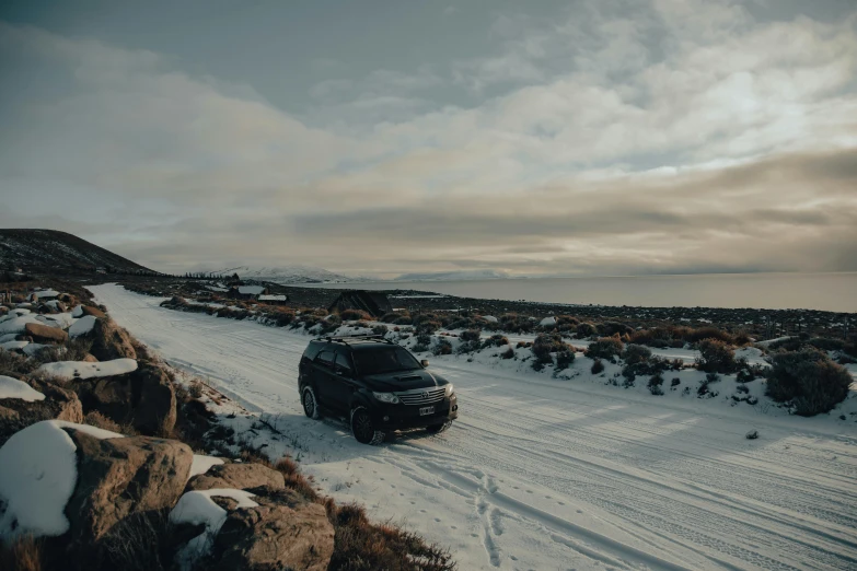 two cars are on a snowy road and one is parked