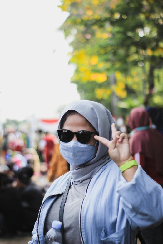 a woman wearing a headscarf holds up a peace sign