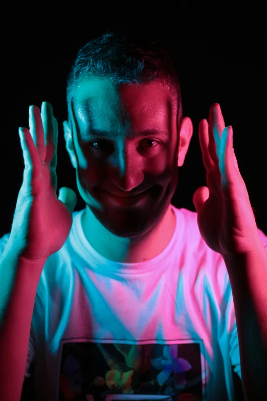 young man with hands up on colored light