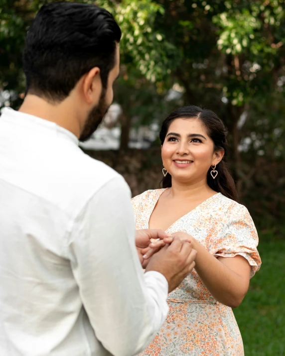 a man and woman in the park with one arm around another, holding the other by the chest