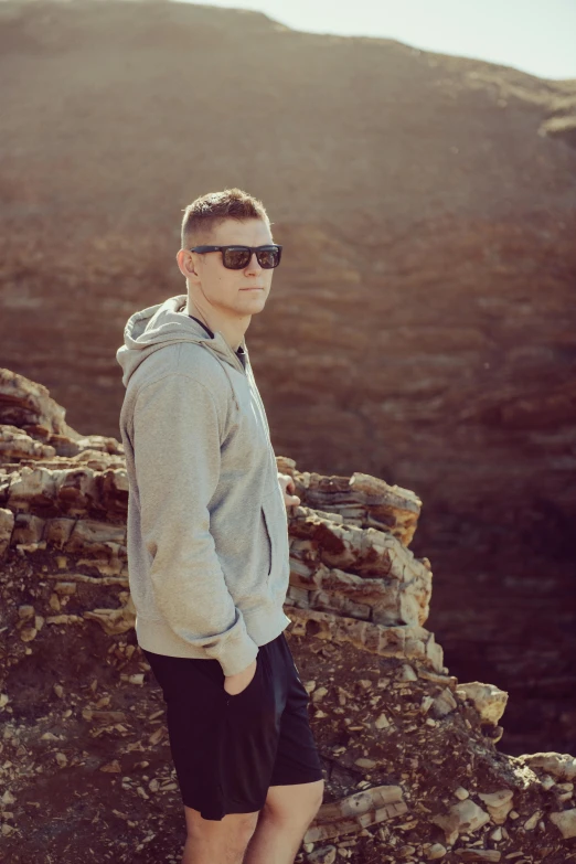 young man in sunglasses on top of a rock formation