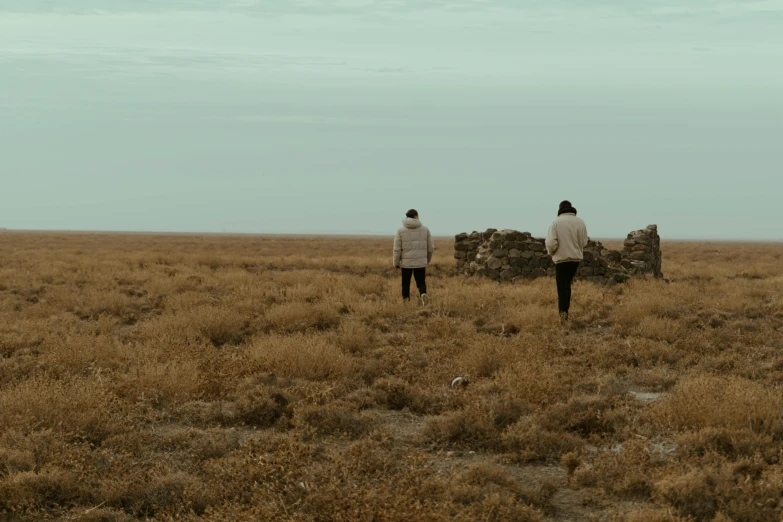 two women stand in an open field looking back at soing