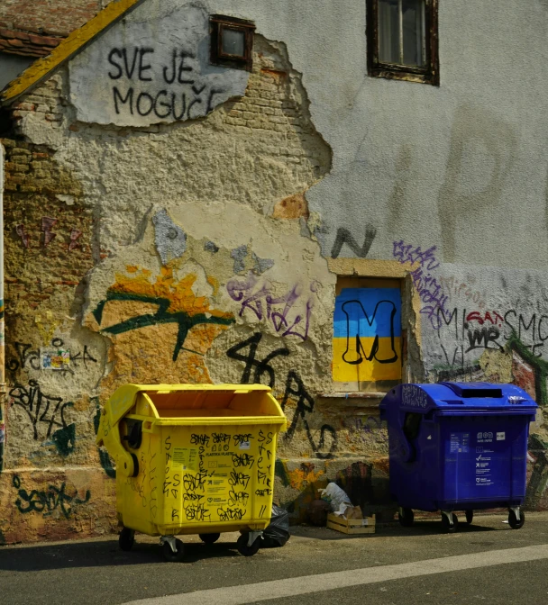 graffiti covered wall with mottles and trash containers