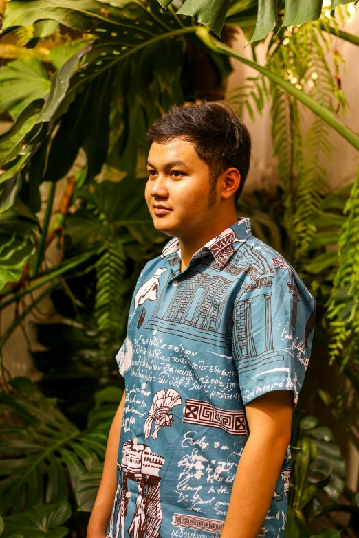 a man in blue shirt standing near plants and bushes