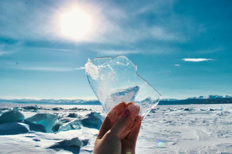 someone holding up an iceberg in the sun