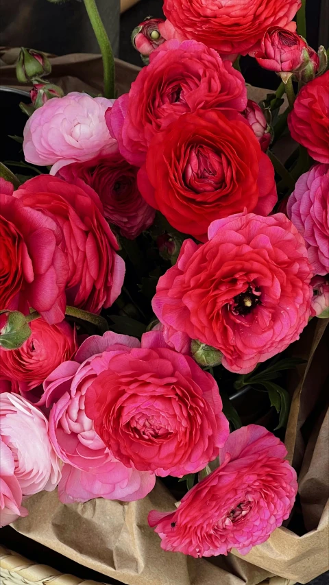 bunches of pink and red flowers placed in brown paper