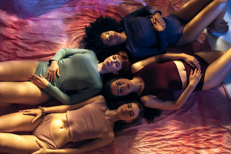 four ladies laying in an empty bed in shorts