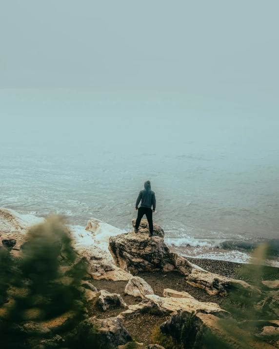 a person standing at the end of a rocky shore