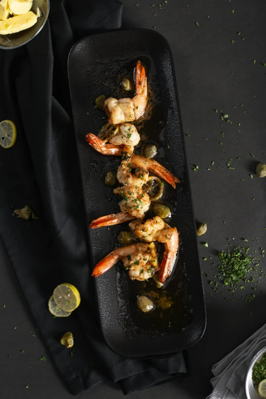 cooked shrimp with garlic and herbs on a black platter