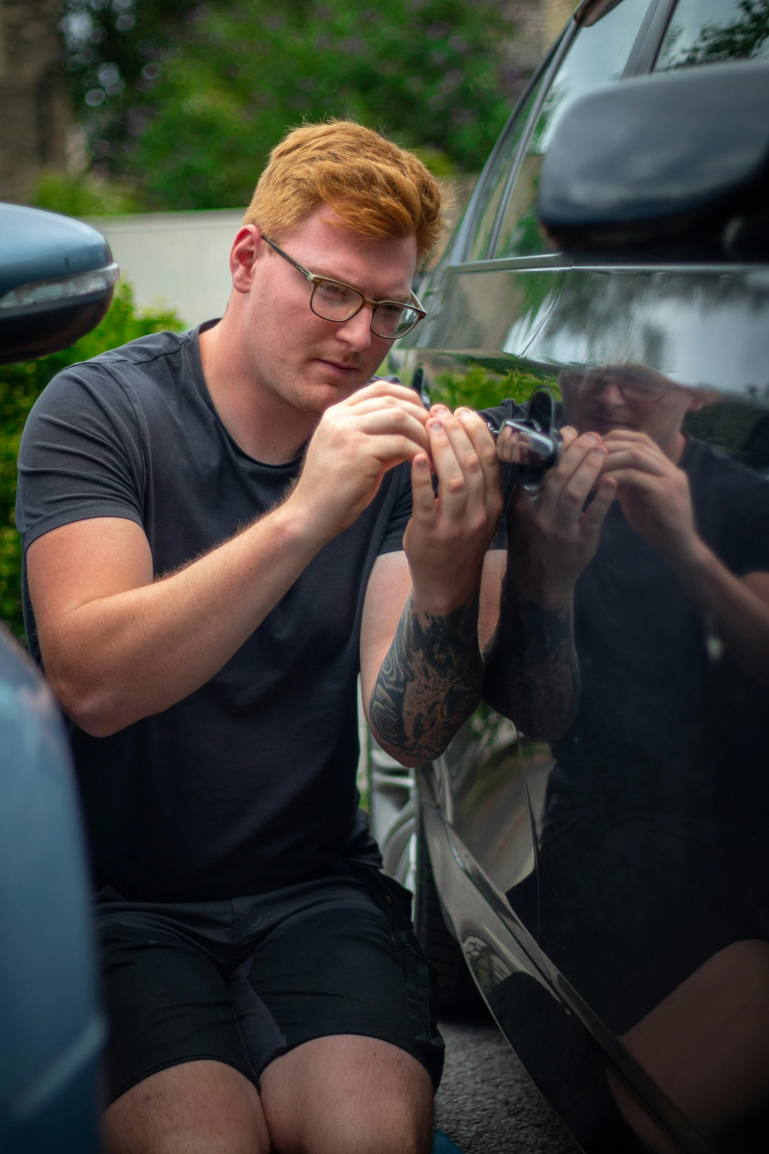 a man with red hair holding onto a car door mirror