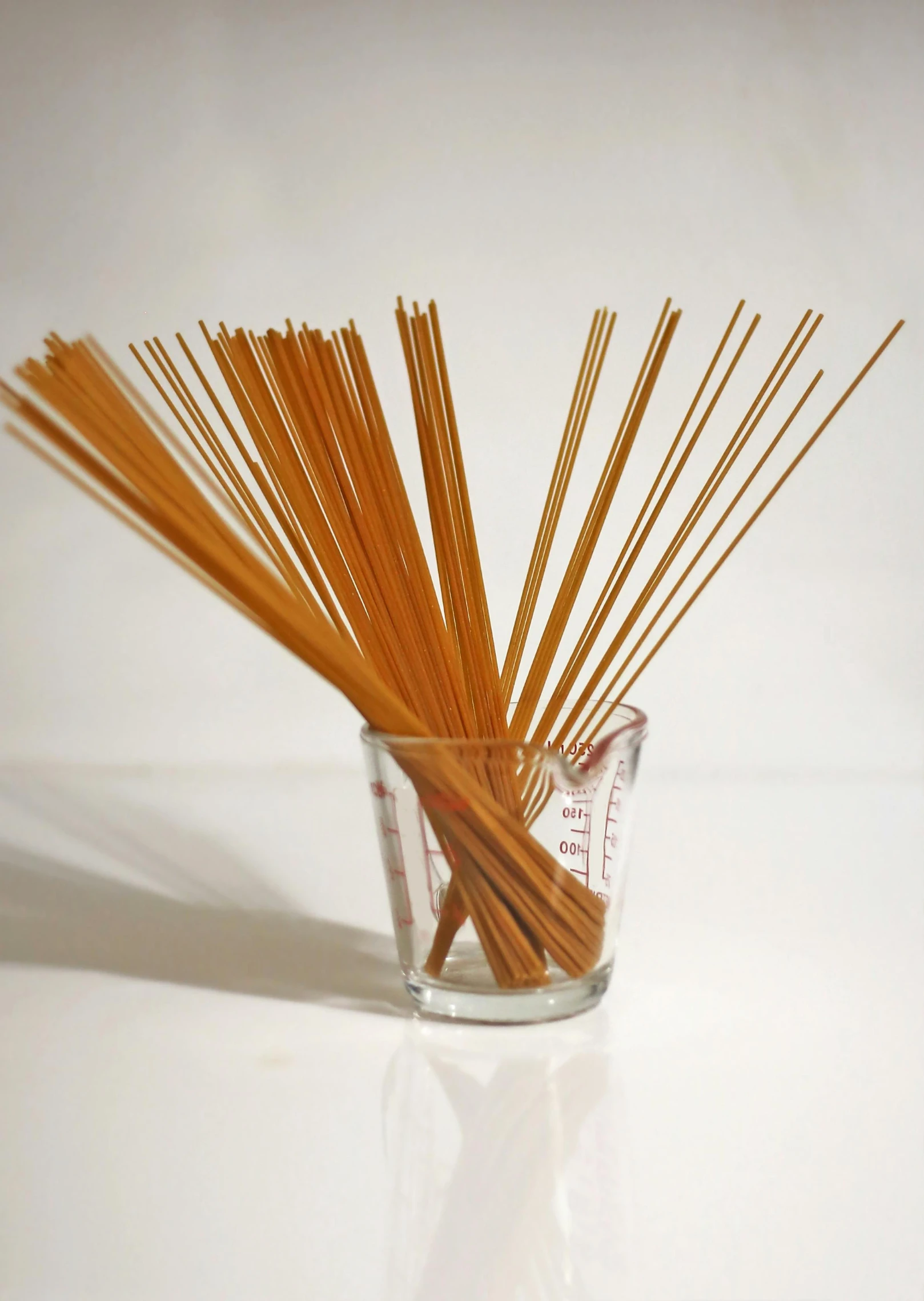 a glass holding some brown straws on a white table