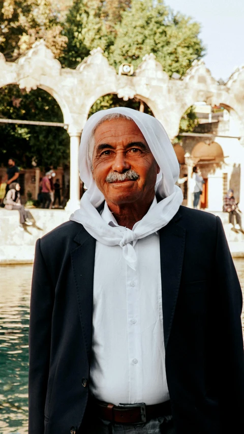 an old man wearing a suit and tie standing in front of a fountain