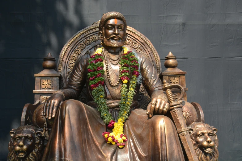 a bronze statue sits near a dark background