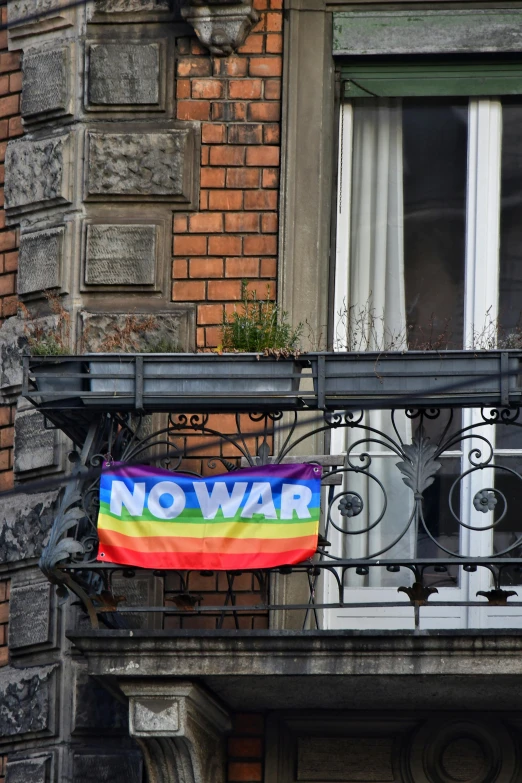 a rainbow flag hanging on a balcony above the window