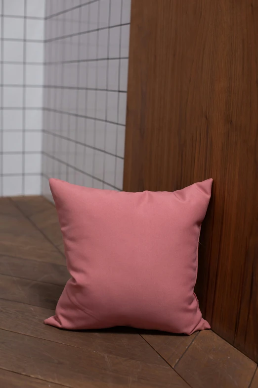 a pink pillow on a wooden floor