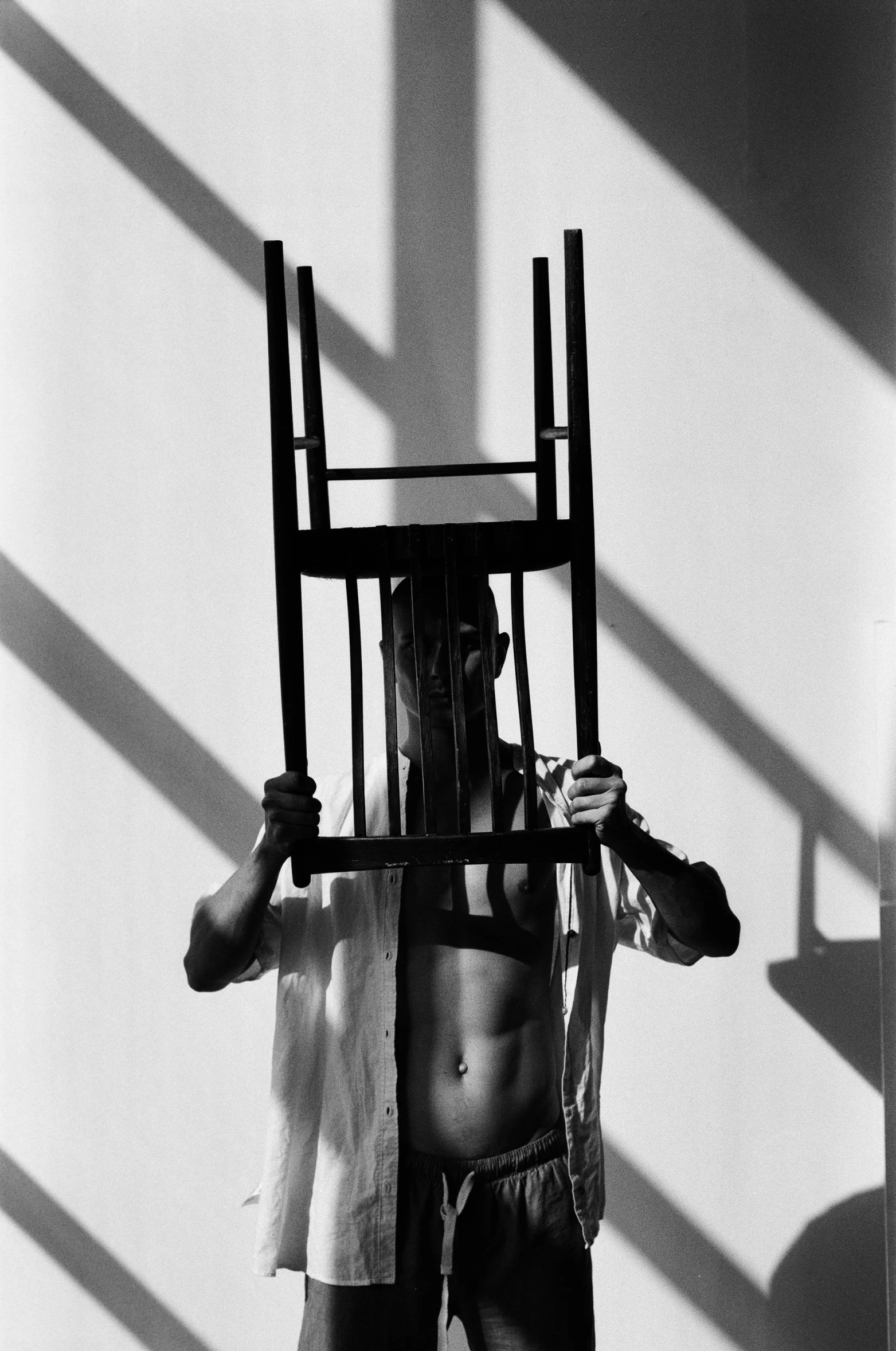 a man with  on is holding up a wooden chair