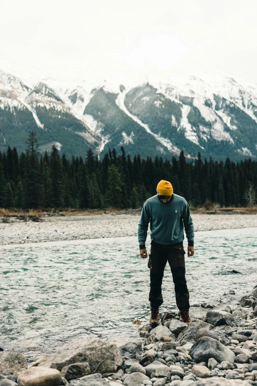 the man is standing on rocks in the middle of a river