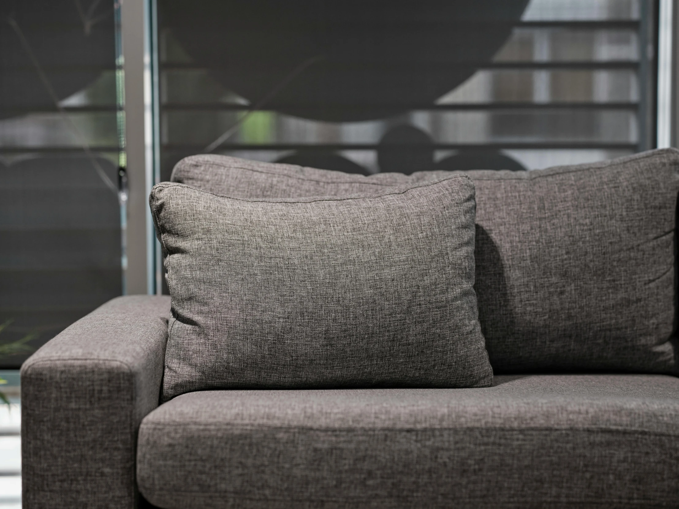 a gray couch with pillows is shown with a wall - to - floor window
