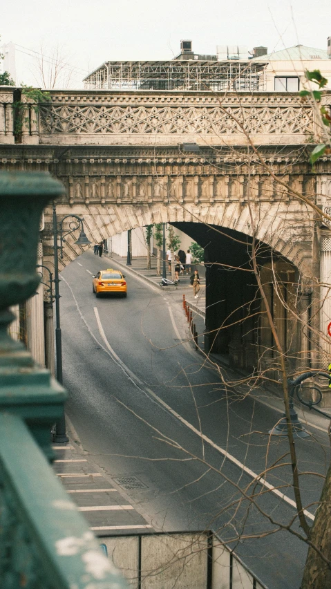 a small yellow car drives under an old archway