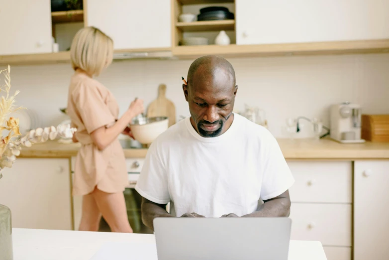 a black man is on his laptop in the kitchen