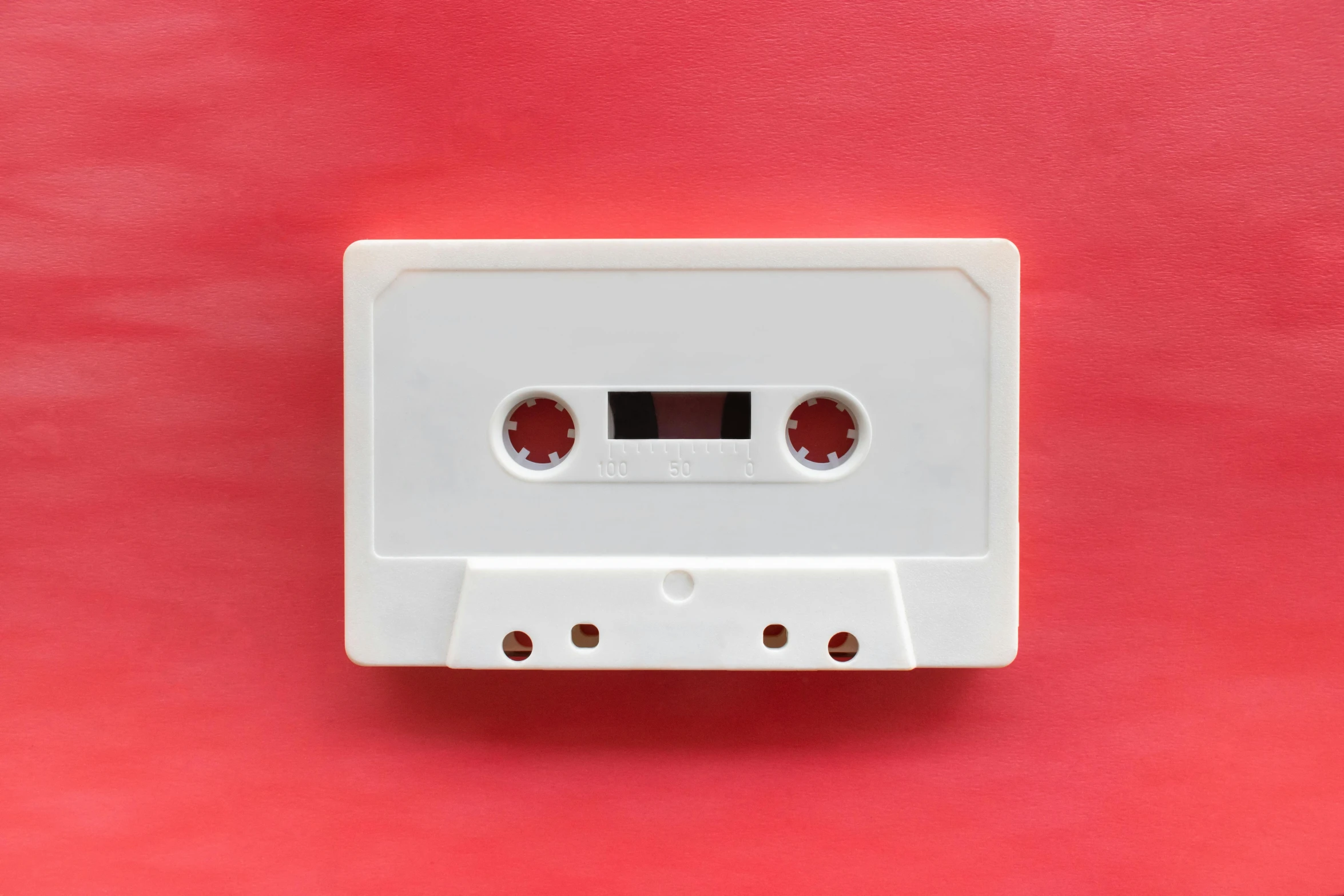 a white cassette shaped object sitting on a red surface