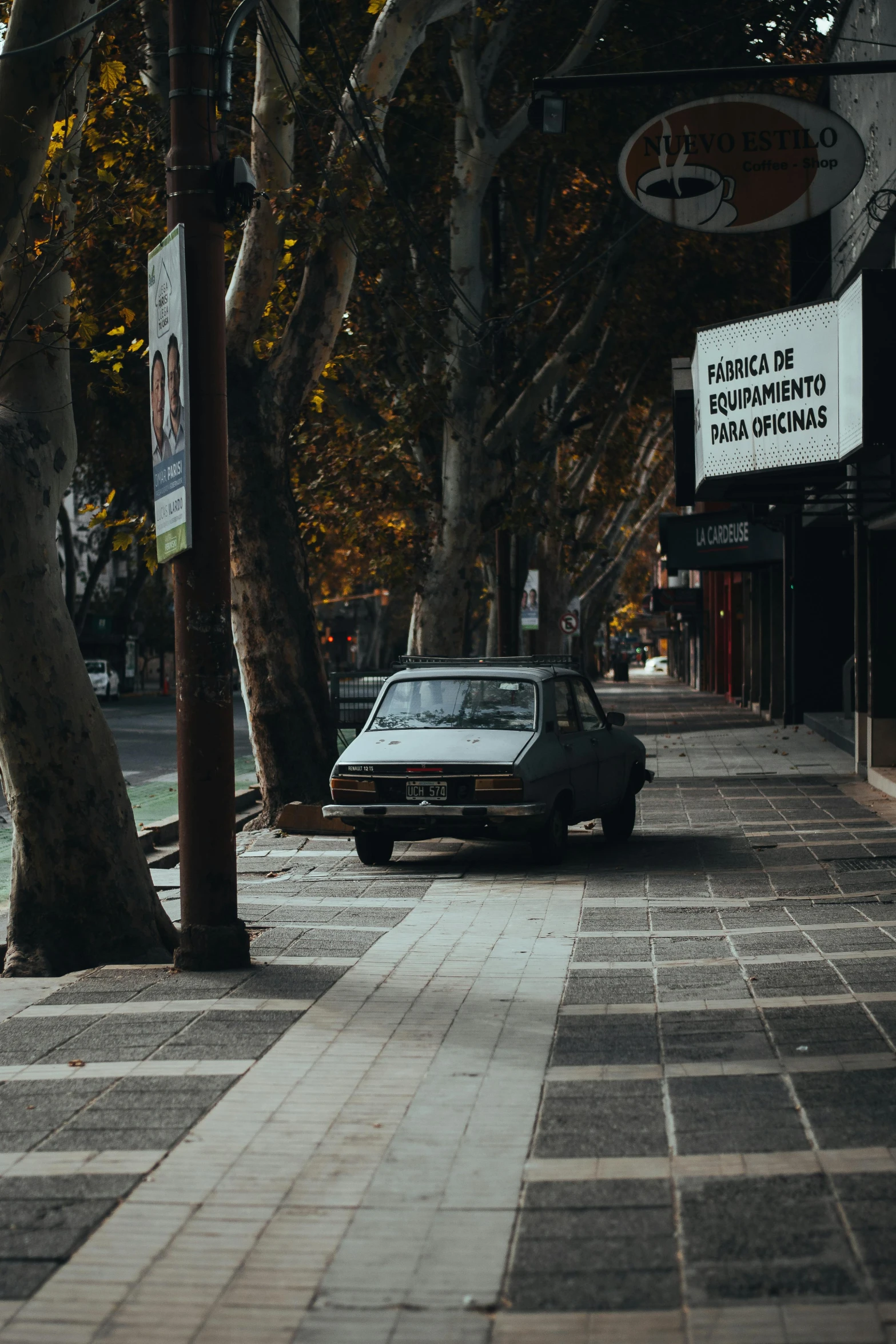 an old - fashioned car sits parked on a street in a tree lined city