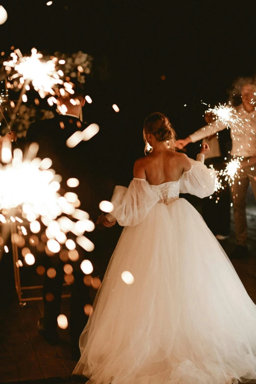 a woman wearing a white wedding dress with a sparky bouquet