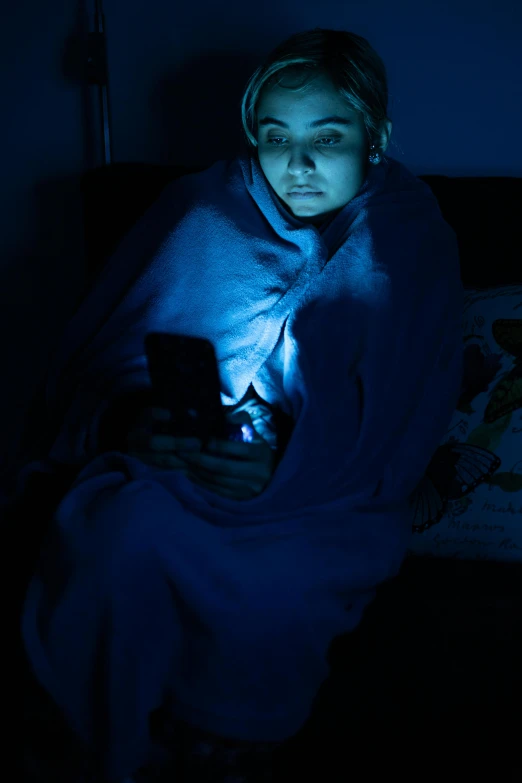 the woman is wrapped in a blanket using her phone
