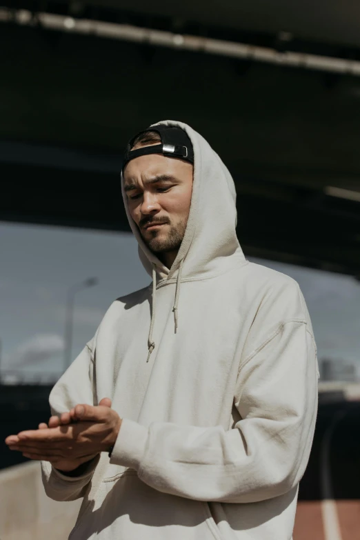 a man is shown wearing a hoodie and standing by a wall