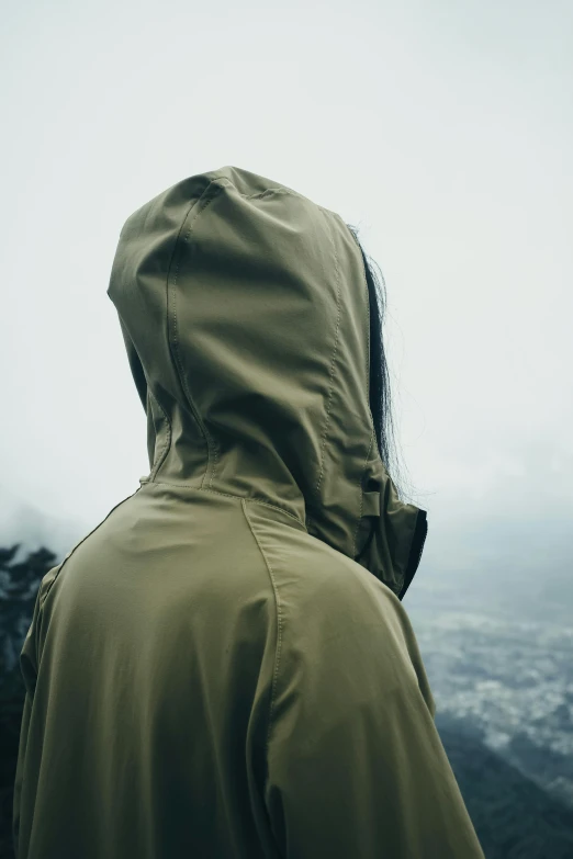 man wearing hooded coat in the mountains in fog