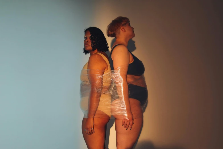 two people in bathing suits that are standing up against a wall