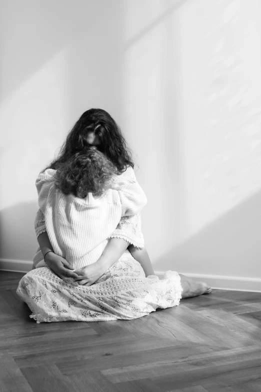 a woman sitting on a floor while holding her hands over her knees