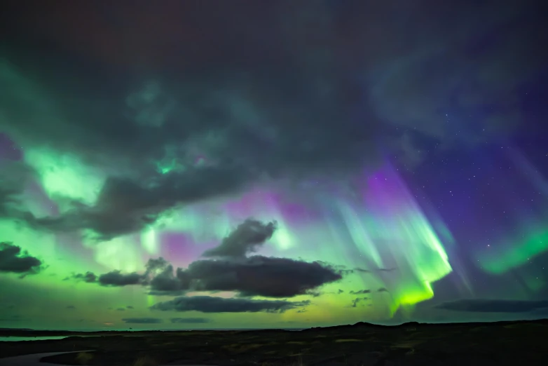 the sky above a body of water is illuminated with many aurora lights