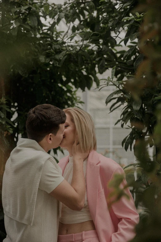 a young man and woman kiss while standing outside