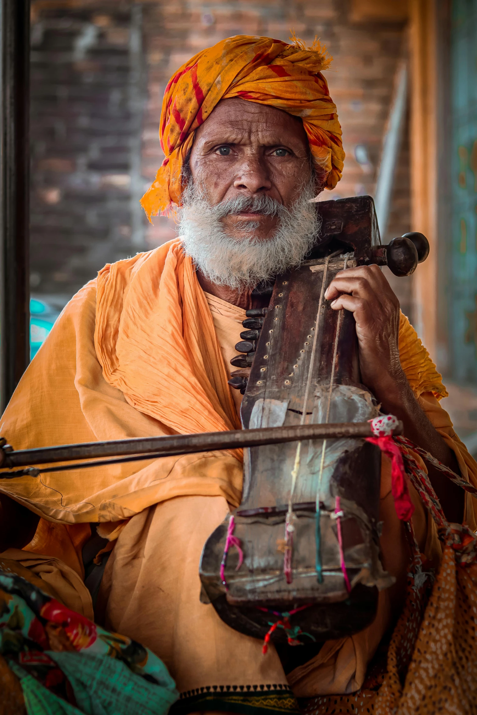 an indian man is wearing orange and holding a instrument