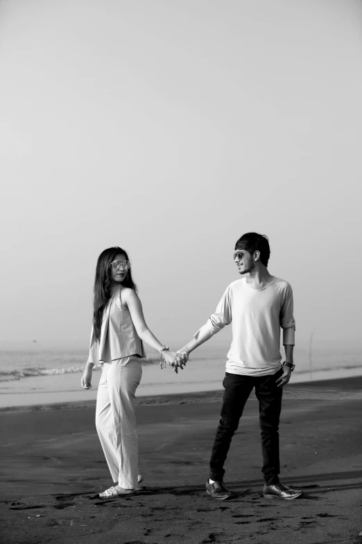 black and white po of two people holding hands on the beach