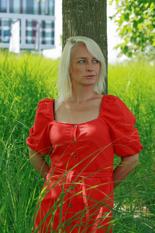 a blond haired woman standing in tall grass