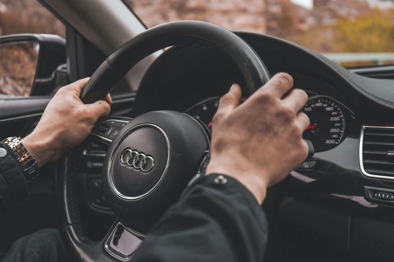 hands on the steering wheel of a vehicle with a brown dashboard