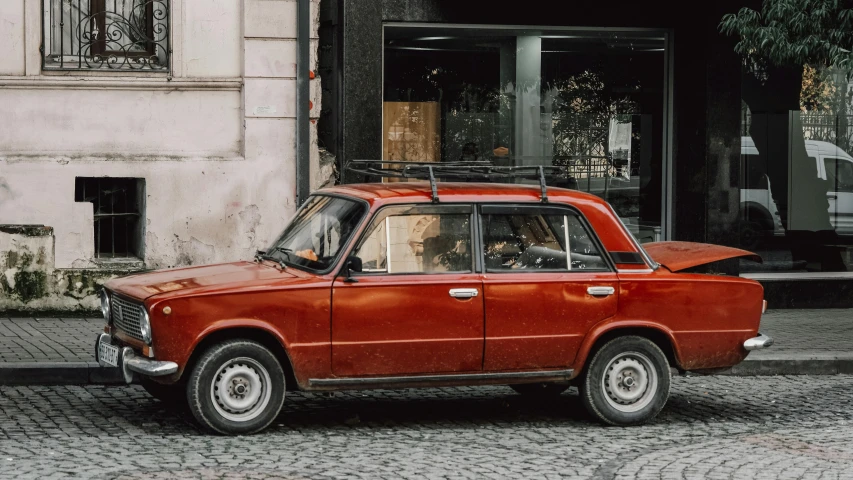 a red car parked on the street with a man sitting in the driver seat