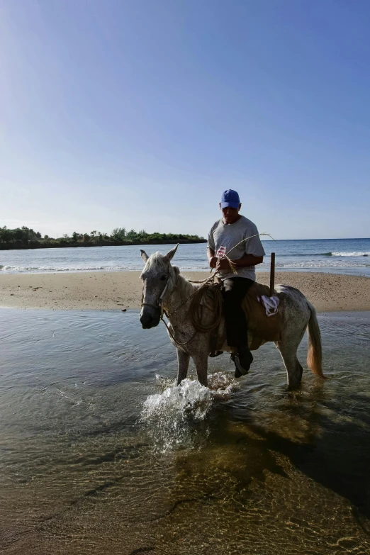 a person riding a horse through water at the beach