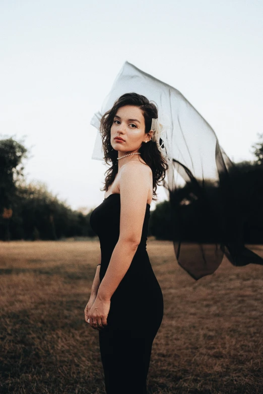 a woman in black dress standing with an umbrella