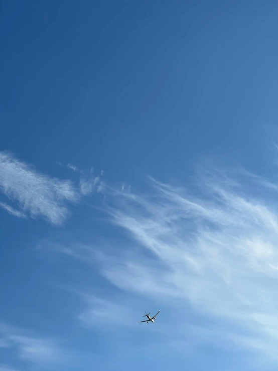 an airplane flying high in the air near a few clouds