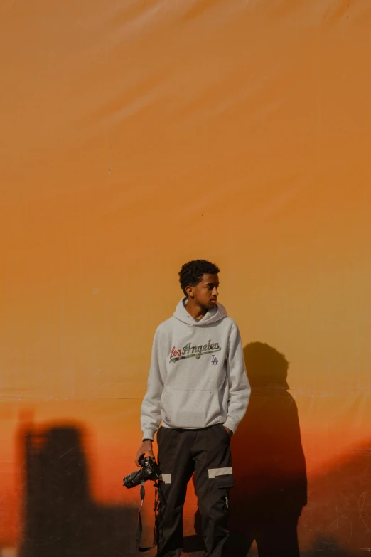 a boy with a camera standing in front of a orange background