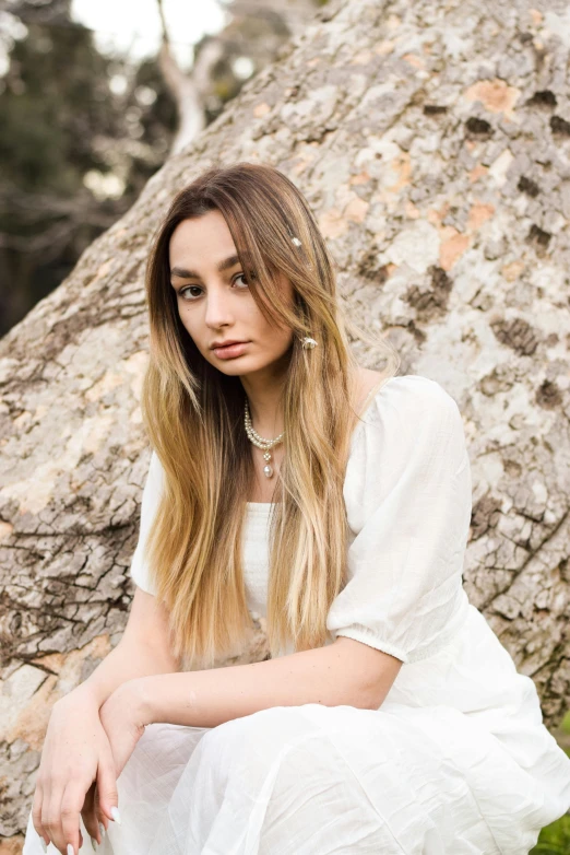 young woman in a white dress sitting on the ground