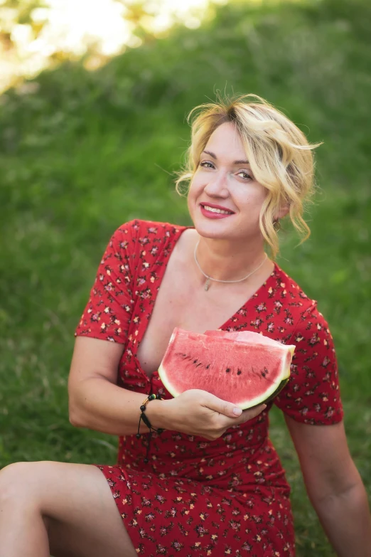 a woman in a dress holds a slice of watermelon