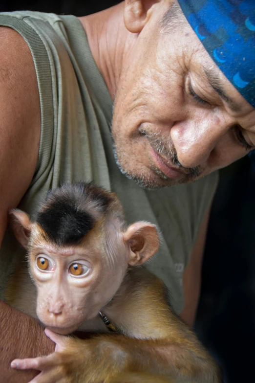 a man holding a small monkey in his lap