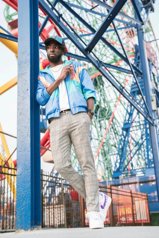 a man wearing white sneakers standing in front of a carnival roller coaster