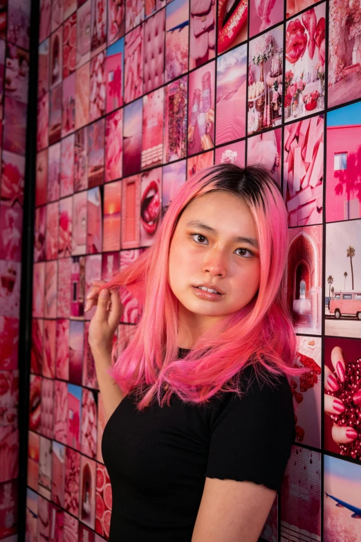 a girl with pink hair in a black shirt next to pink wall